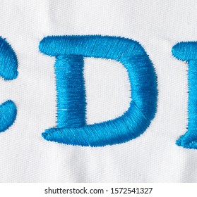 
Embroidered Alphabet Letters In Blue Line On White Fabric