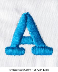 
Embroidered Alphabet Letters In Blue Line On White Fabric