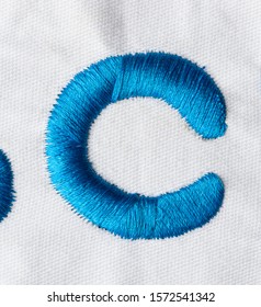 
Embroidered Alphabet Letters In Blue Line On White Fabric