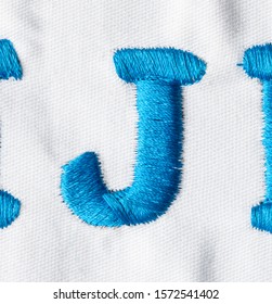 
Embroidered Alphabet Letters In Blue Line On White Fabric