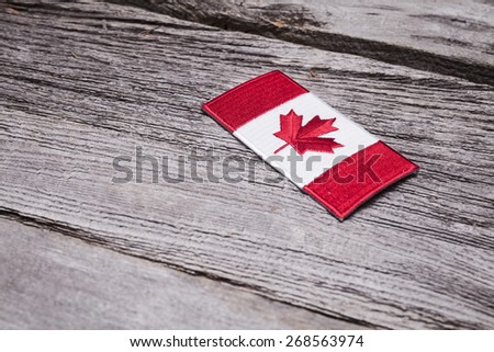 An embroidered Canadian flag patch sits on a rustic wooden background.
