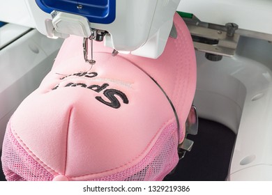 Embroidered Pink Cap On The Hoop Of White Embroidery Machine, Close Up Image