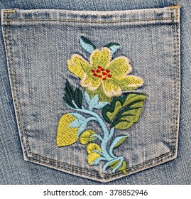  Embroidered yellow flower on blue jeans denim pocket, close up, Oktoberfest fashion background  - Powered by Shutterstock