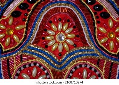 Embroidery with beads, glass beads and glass beads on a red background. Decor for clothes in folk style.