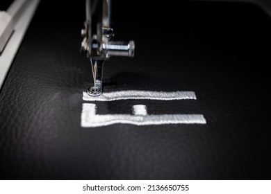 Embroidery design on black leather with white thread. Embroidery by machine. Close up.