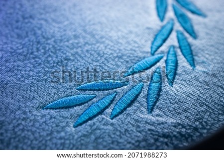 Embroidery design on blue towel with blue thread. Embroidery by machine. Close up.
