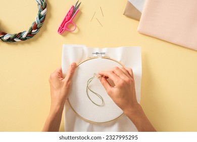 Embroidery needlework concept. Colorful threads and embroidery hoop with fabric in female hands.