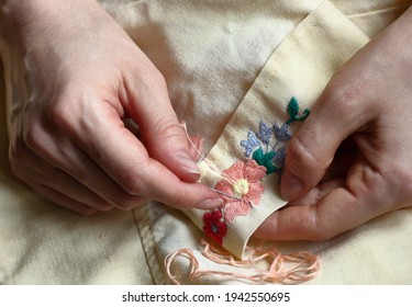 Embroidery in woman hands, female doing flower pattern embroidery on grandma natural clothes, closeup, cottagecore living, eco lifestyle, slow simple living and digital detox concept