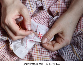 Embroidery in woman hands, female doing flower pattern embroidery on children natural clothes, closeup, cottagecore living, eco lifestyle, slow simple living and digital detox concept