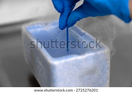 Embryologist in blue gloves using liquid nitrogen for cryopreservation of embryos and eggs in IVF lab, vitrification process in fertility clinic for assisted reproductive technology and pregnancy.