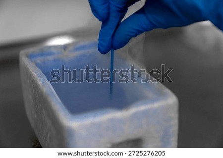 Embryologist in blue gloves using liquid nitrogen for cryopreservation of embryos and eggs in IVF lab, vitrification process in fertility clinic for assisted reproductive technology and pregnancy.