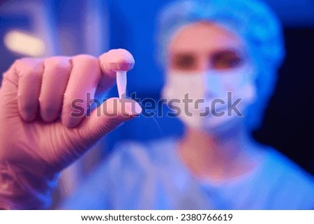 Embryologist is showing cryovial filled with cryopreserved biological samples