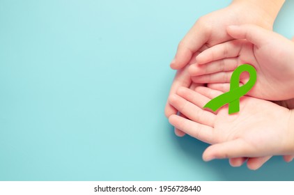 Emerald green color ribbon in doctor and family hand for Liver Cancer and Hepatitis B disease awareness.Mental health day.Liver Cancer Awareness Month.treatment care, Support, charity, Hope.medical.