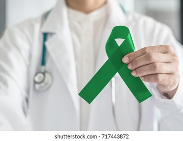 Emerald green or jade color ribbon in doctor's hand symbolic for Liver Cancer and Hepatitis B disease awareness concept

