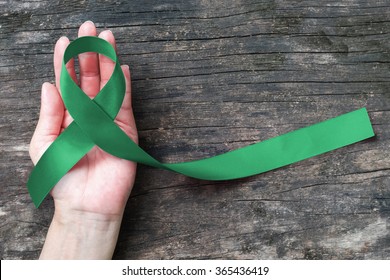 Emerald Green (Jade) ribbon awareness color on helping hand for Liver Cancer and Hepatitis B - HVB month (isolated with clipping path)