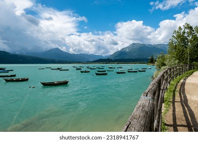 The emerald green lake of Santa Croce, surrounded by the beautiful Venetian Dolomites in the province of Belluno. Italy, with the characteristic wooden boats in Poiatte. June 10, 2023