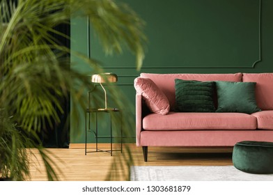 Emerald Green Pillows On Pastel Pink Couch In Stylish Living Room Interior With Dark Green Wall