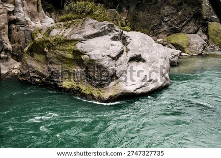 Emerald mountain river flowing through rocky gorge surrounded by dense forest and misty hills in North Sikkim. 