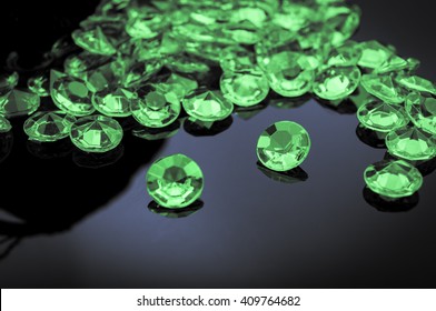 Emeralds Scattered On A Shiny Surface With Prominent Emerald In The Middle