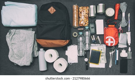 Emergency Backpack Equipment Organized On The Table. Documents, Water,food, First Aid Kit And Another Items Needed To Survive.