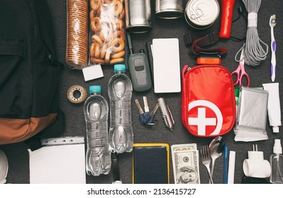 Emergency Backpack Equipment Organized On The Table. Documents, Water,food, First Aid Kit And Another Items Needed To Survive.