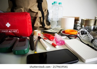 Emergency Backpack Equipment Organized On The Table. Documents, Water,food, First Aid Kit And Another Items Needed To Survive.