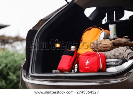 Emergency backpack, first aid kit and necessities in trunk of car outdoors, closeup