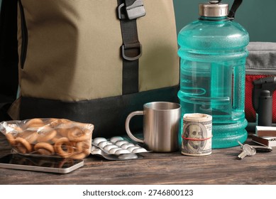 Emergency backpack with necessities on table near green wall, closeup