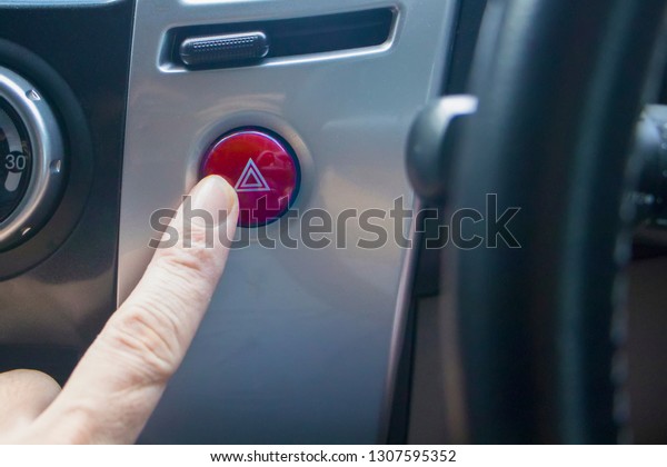 Emergency button in the car.finger hitting car\
emergency light\
botton