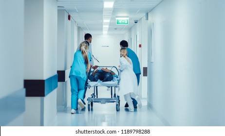 Emergency Department: Doctors, Nurses and Paramedics Push Gurney / Stretcher with Seriously Injured Patient towards the Operating Room. Bright Modern Hospital with Professional Staff Saving Lives. - Shutterstock ID 1189798288