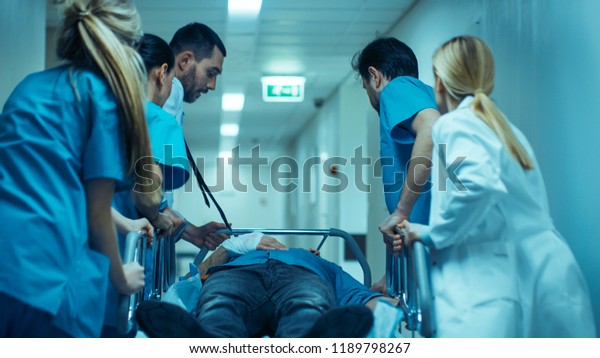 Emergency Department: Doctors, Nurses and\
Surgeons Move Seriously Injured Patient Lying on a Stretcher\
Through Hospital Corridors. Medical Staff in a Hurry Move Patient\
into Operating\
Theater.