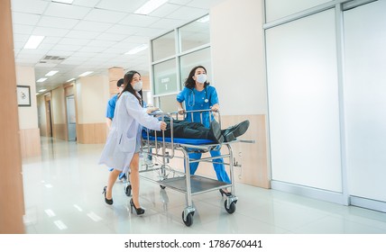 Emergency Department, Doctors And Surgeons Team Move Seriously Injured Patient Lying On A Stretcher Through Hospital Corridors. Medical Staff In A Hurry Move Patient Into Operating Room