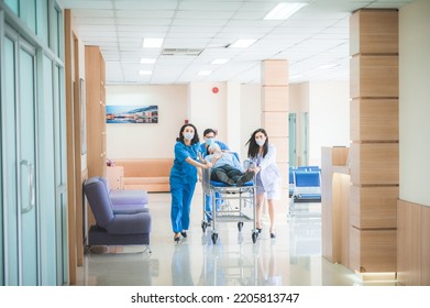 Emergency Department,  Medical Team With Doctors, Nurses And Surgeons Are Pushing Seriously Injured Patient Emergency Stretcher Bed In The Hospital Corridor