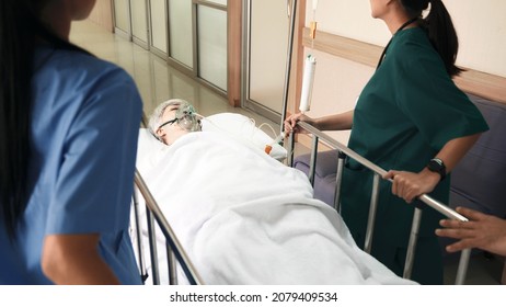 Emergency Department. Nurse and senior doctor team busy push emergency stretcher transport senior patient in hospital, doctors, nurses in surgical gown and white coat uniform running with hurry
