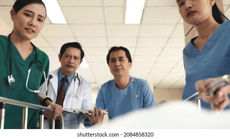 Emergency Department. Nurse And Senior Doctor Team Busy Push Emergency Stretcher Transport Senior Patient In Hospital, Doctors, Nurses In Surgical Gown And White Coat Uniform Running With Hurry