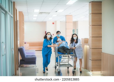 Emergency Department Staff Push Gurney With Seriously Heart Attacked Patient Towards The Operating Room. Bright Modern Hospital With Professional Staff Saving Lives.