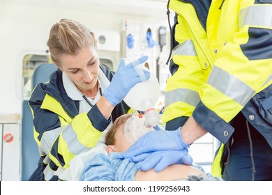 Emergency doctor giving cardiac massage for reanimation in ambulance to woman - Powered by Shutterstock