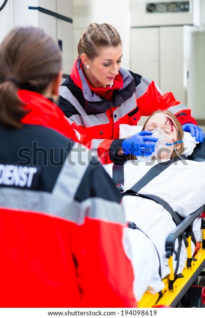 Emergency doctor and nurse or ambulance team\
transporting accident victim on\
stretcher