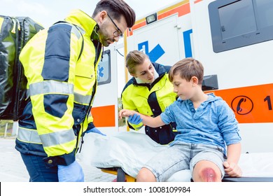 Emergency doctors caring for accident victim boy sitting on stretcher - Powered by Shutterstock