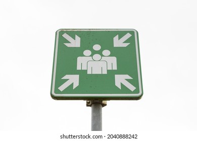 An emergency evacuation assembly point sign on a pole on a white background