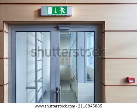 Emergency exit with glass door in airport office building. Emergency fire doors. Rescue signs icon green emergency exit lamp