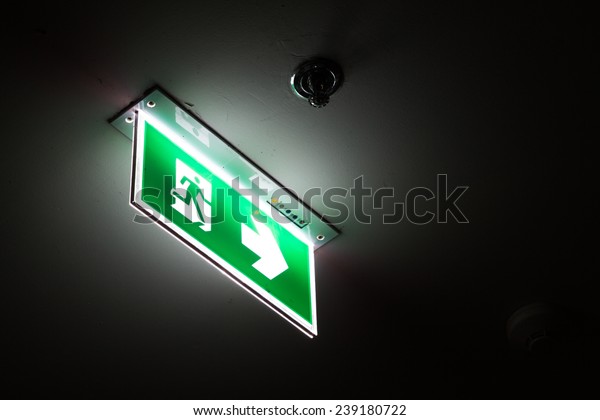 Emergency exit\
sign above a black doorway at\
night.