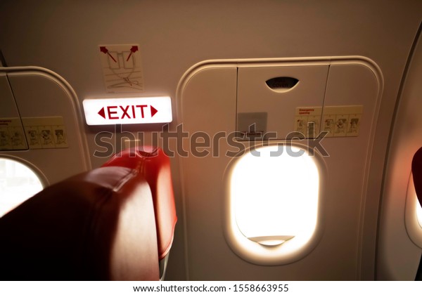 Emergency Exit Signs Red letters\
on the inside wall of the plane in front of the passenger seat in\
front of the sign and the two-side windows are the emergency\
exit.
