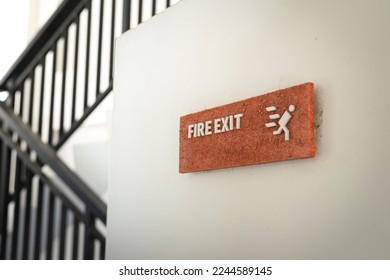 An emergency fire exit direction plate that installed on the white door. Safety sign for transportation mode object photo, close-up and selective focus.
