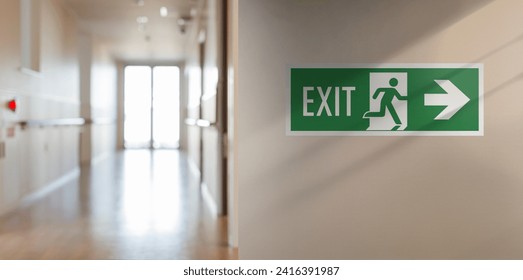 Emergency fire exit sign in the corridor of the school. Arrow on the right, blurred background with copy space for text and messages.