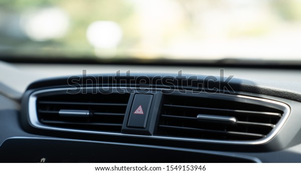 Emergency light button on dashboard of car between\
two air vents