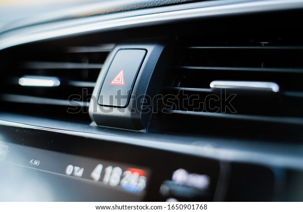 The emergency light button in the sedan is\
near the air conditioner.