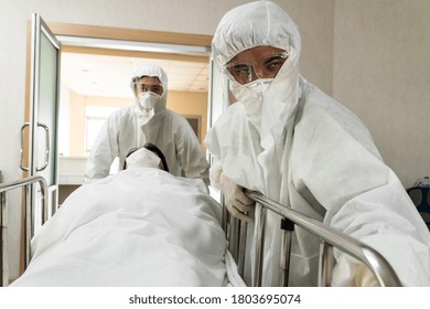 Emergency Medic And Doctor Moving Patient To Emergency Room In Hospital . Doctor Wears Protective Suit And Face Mask In Concept Of Coronavirus And Covid 19 Protection And Quarantine .