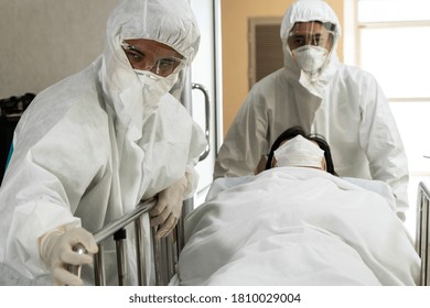 Emergency Medic And Doctor Moving Patient To Emergency Room In Hospital . Doctor Wears Protective Suit And Face Mask In Concept Of Coronavirus And Covid 19 Protection And Quarantine .