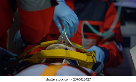 Emergency medical doctors providing medical help for patient in oxygen mask. Health care professionals rescuing victim of drill car crash. EMS paramedics fixing man head on stretchers in ambulance car - Powered by Shutterstock